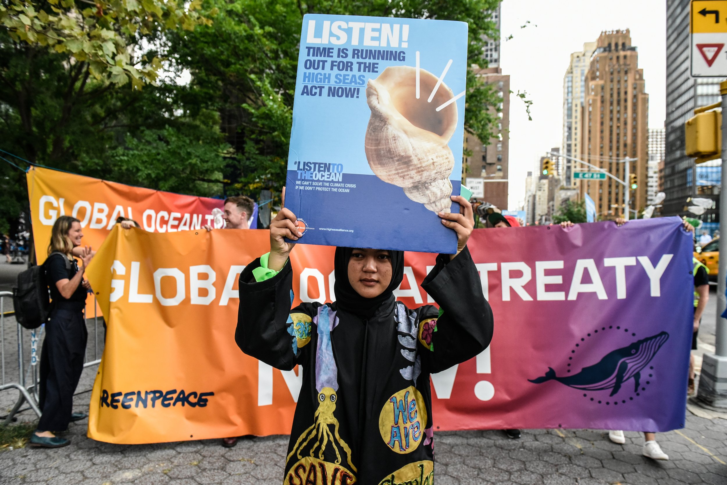Khaireeyah Ramanyah holding a sign that reads "Listen! Time is running out for the high seas. Act Now!"