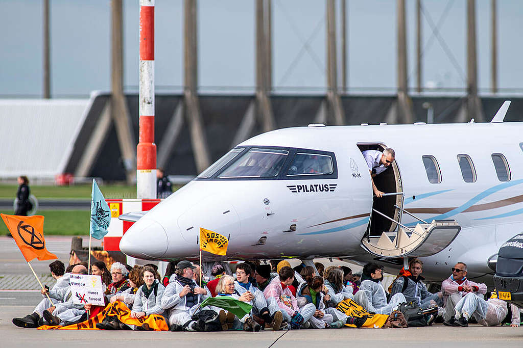A large group of activists from Extinction Rebellion and Greenpeace Netherlands hold a peaceful protest at Amsterdam Schiphol Airport, the second biggest in the EU, stopping private jets from landing and taking off and sitting and cycling around the area where private jets are parked. © Marten  van Dijl / Greenpeace 
