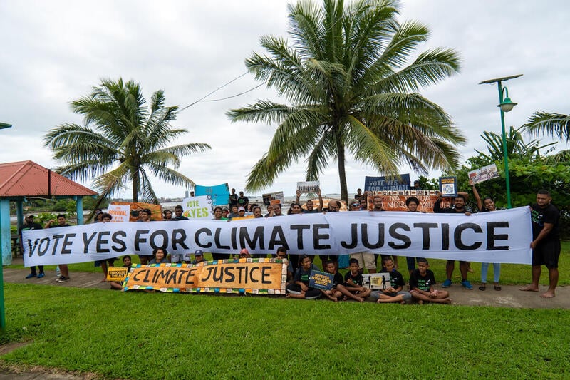Youth activists hold a banner that reads: Vote Yes for Climate Justice. © Eremasi Rova / Greenpeace