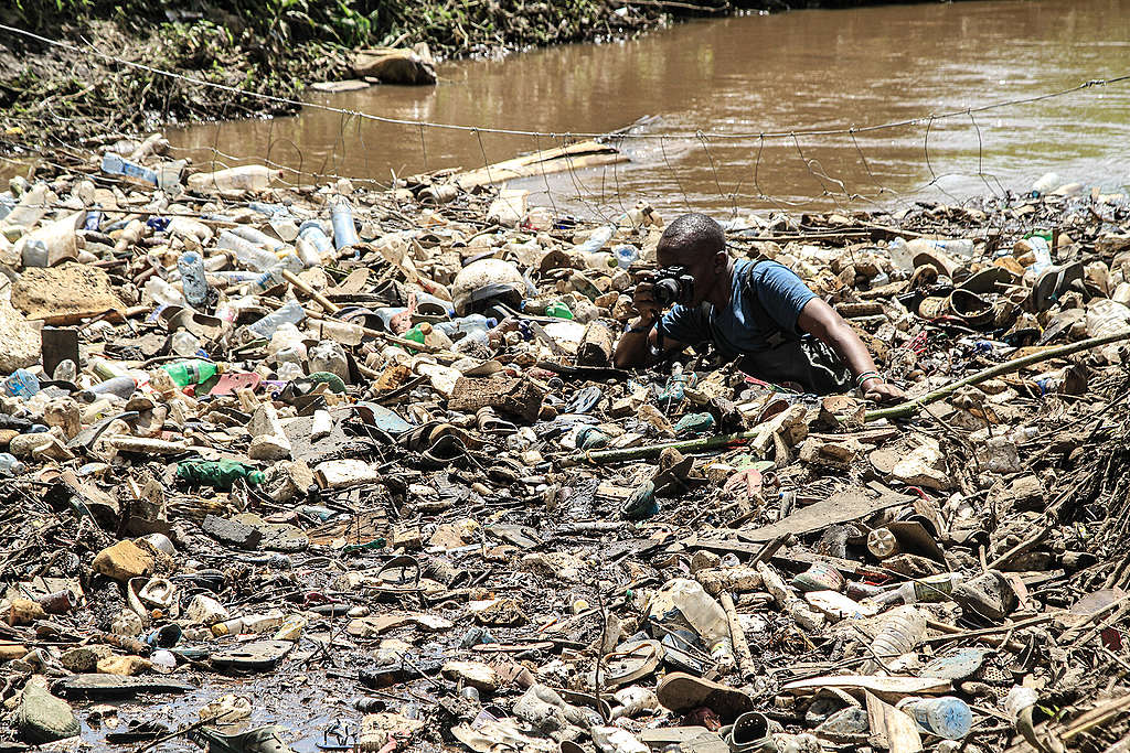 James collecting plastic waste at Njoro River In Nakuru. © Bedan Mwihia