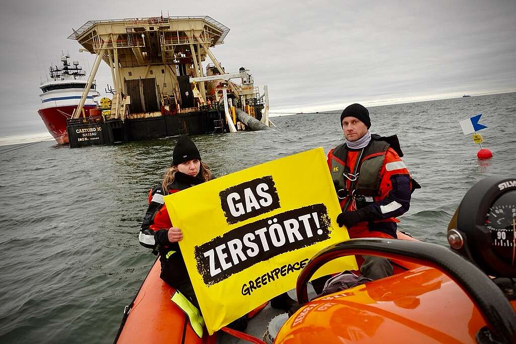 In a protest against the laying of a gas pipeline between the port of Lubmin and Mukran on the island of Rügen with the pipeline laying ship "Castoro 10", about two kilometers off the coast of Rügen, Greenpeace activists on an inflatable boat hold a banner reading "Gas Destroys". At the same time two other activists dive five meters below the water surface, and set up an air sack on the pipeline, which is lowered to the seabed at the stern of the ship. "Gas destroys!" is written on the outer wall of their underwater tent, where they can stay for a longer period of time. © Ruben Neugebauer / Greenpeace