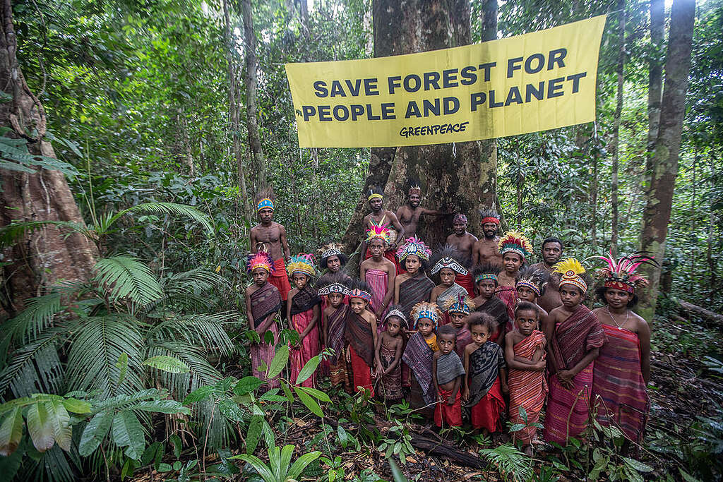 Women and young people of Knaisaimos-Tehit with yellow banner "Save Forest for People and Planet" © Jurnasyanto Sukarno / Greenpeace