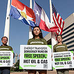 Greenpeace USA activists stand outside Dallas City Hall in Texas with signs for a recent campaign aimed at Energy Transfer. 