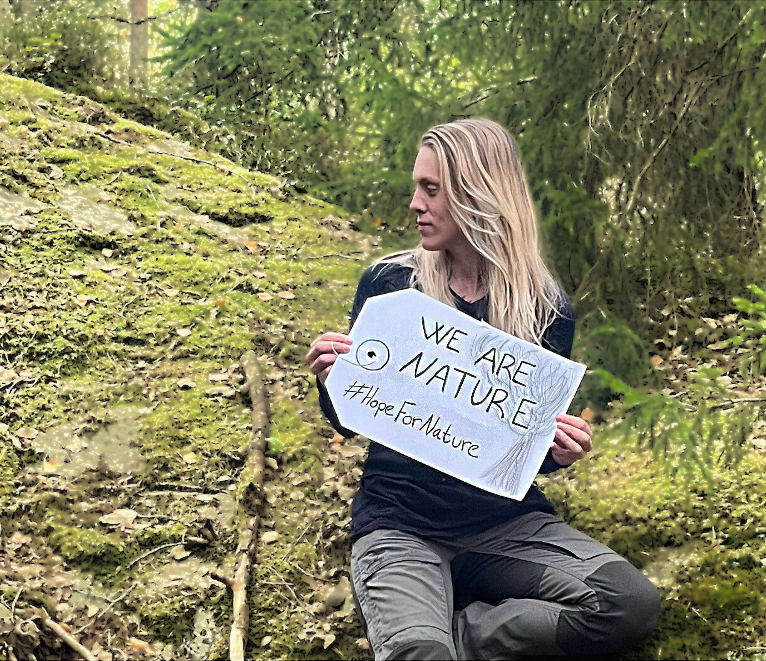 activist with banner saying "We are nature #HopeForNature"