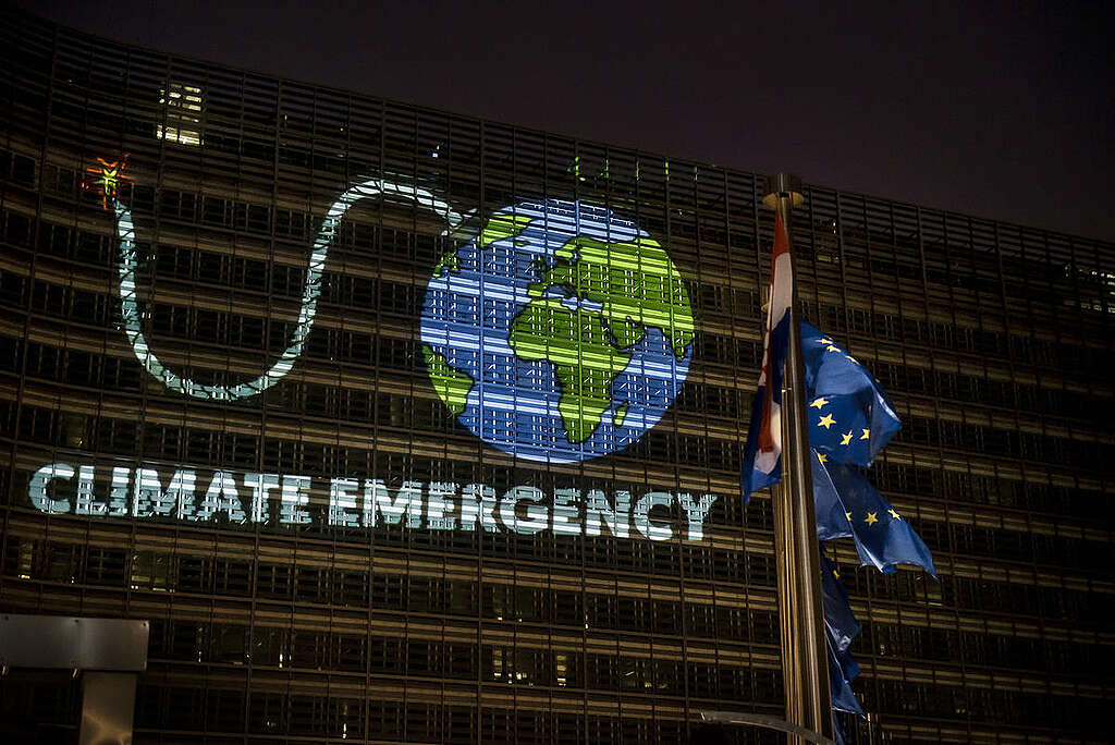 Attivisti di Greenpeace proiettano un'immagine della Terra come una bomba con la miccia accesa presso la Commissione europea