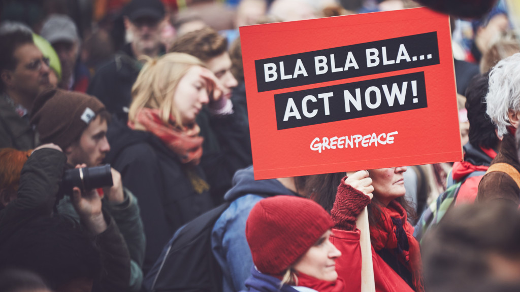 Manifestanti di Greenpeace con cartello "Act Now".