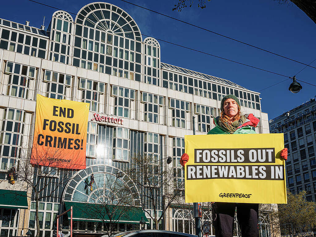 Attivista di Greenpeace alla Conferenza Europea del Gas di Vienna regge un cartello con scritto "no combustibili fossili, sì rinnovabili"