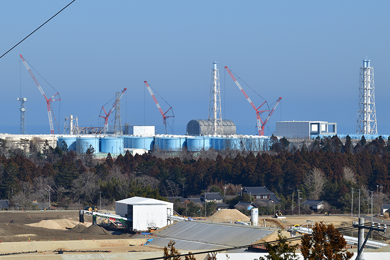 汚染水タンクの向こうに福島第一原発1～4号機が並ぶ