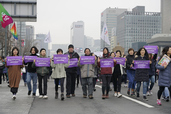 국제환경단체 그린피스 활동가들이 3월 4일(일) 광화문에서 진행된 제34회 한국여성대회에 참여하여, 미투 운동 연대를 의미하는 위드유 동참 현수막을 들고 평화 행진을 하고 있다. 그린피스는 성폭력과 착취, 차별로 인한 피해자들과 연대하고 미투 운동을 지지한다고 선언했다.