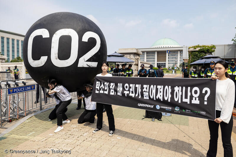 청년들이 국회 앞에서 공정한 탄소예산 배분을 요구하며 탄소의 짐 퍼포먼스를 펼치고 있다.