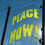 Climbers preparing Peace Now! sign between the masts of the Rainbow Warrior in Istanbul