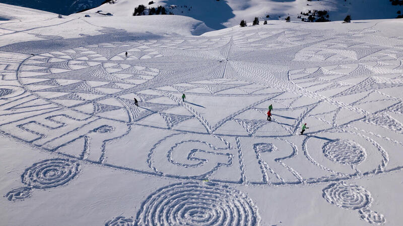 El artista de nieve Simon Beck y activistas de Greenpeace durante la realización de la obra de arte.
Juntos estampan espectacularmente el mensaje "¡La vida por encima del crecimiento!" en la nieve cerca de Davos.