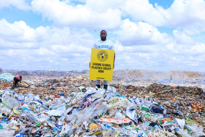 Pancarta en el vertedero de Dondora, Kenia Un voluntario de Greenpeace África con una pancarta en la que se lee "Tratado mundial sobre los plásticos fuerte, ¡ya!" en el corazón del vertedero de Dandora.
