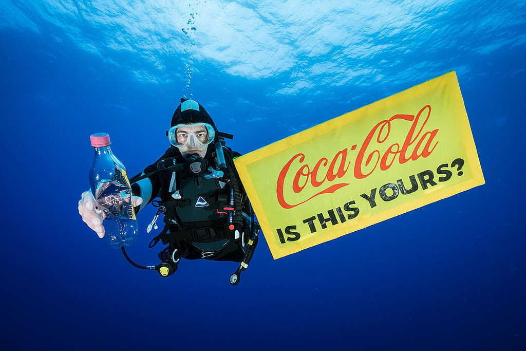 Een Greenpeace duiker houdt een plastic flesje omhoog van Coca-Cola met een banner die leest: "Is this yours". Coca-Cola is verantwoordelijk voor heel veel plastic afval © Justin Hofman