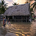 Inwoners van Tuvalu lopen door overstroomde straten.