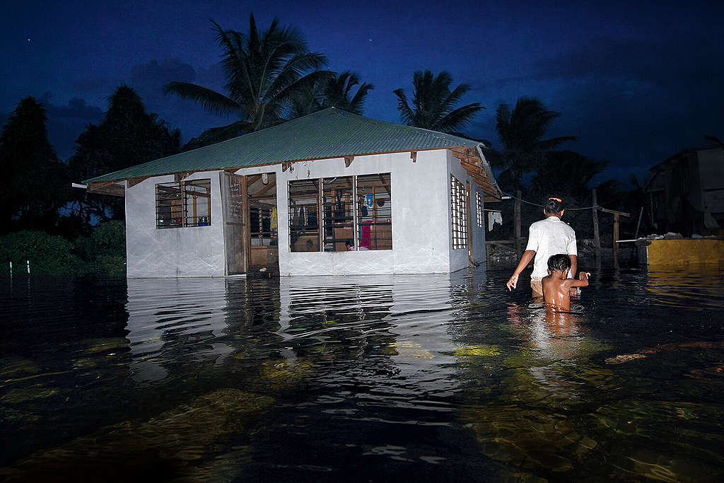 Inwoners van Tuvalu lopen door overstroomde straten. 