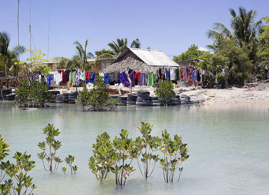 Huizen op Kiribati worden met autobanden beschermd tegen het water dat tijdens vloed steeds dichterbij komt. © Sanne Zurné