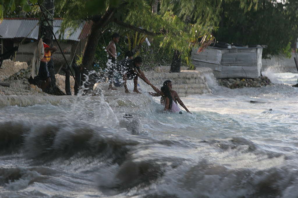 Dorpelingen trekken zich omhoog aan elkaar. De hoge golven worden veroorzaakt door de 'King Tides' op Kiribati.
