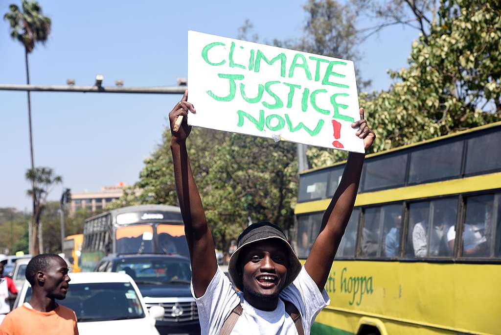 Klimaatactivist met bord Climate Justice Now (Klimaatrechtvaardigheid nu)