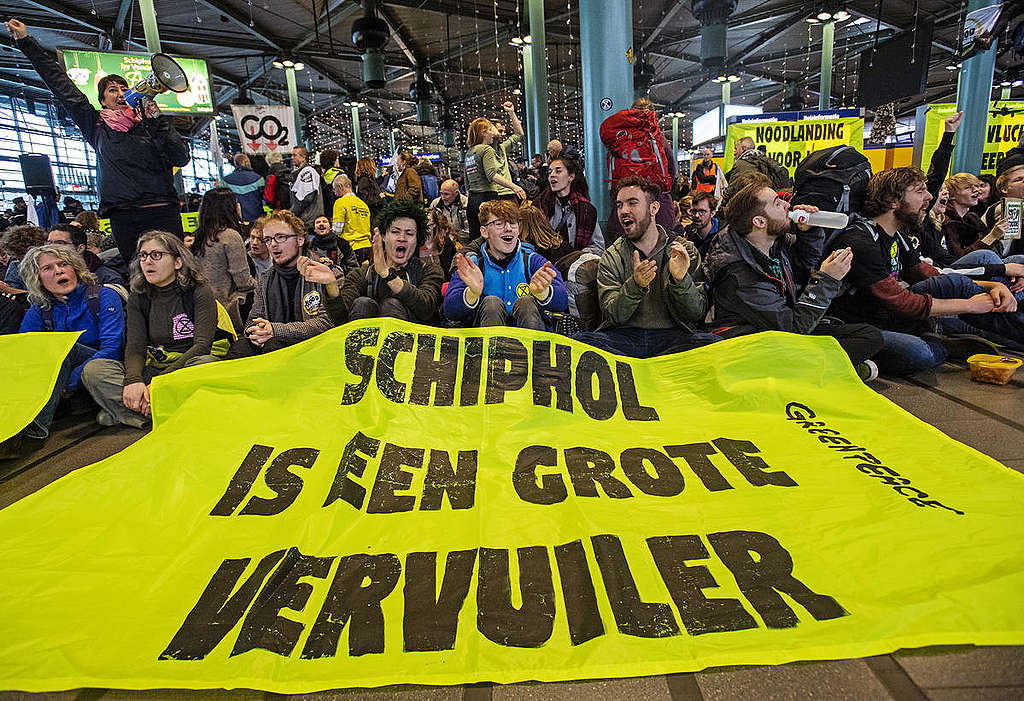 Actievoerders van Greenpeace en Extinction Rebellion op Schiphol met spandoektekst 'Schiphol is een grote vervuiler'