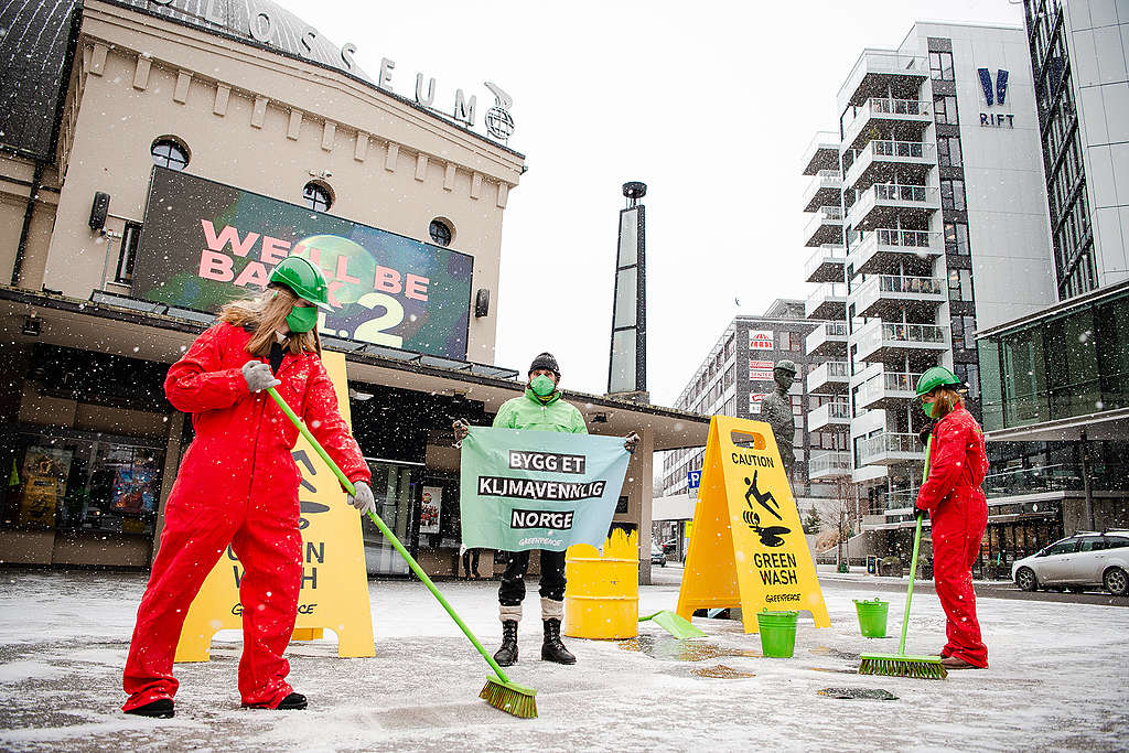 Tre Greenpeace-aktivister utenfor Colosseum kino i Oslo. To har på seg røde kjeledresser og holder i hver sin kost mens de "vasker" bakken. En tredje aktivist holder et banner med teksten "bygg et klimavennlig Norge". 