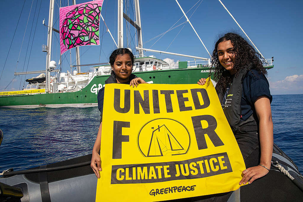 Klimaforkjemperne Watan Mohammed fra Sudan og Alia Hammad fra Egypt holder et banner for klimarettferdighet, "United for Climate Justice", foran Greenpeace-skipet Rainbow Warrior i Middelhavet, i forkant av klimatoppmøtet i Egypt i 2022.