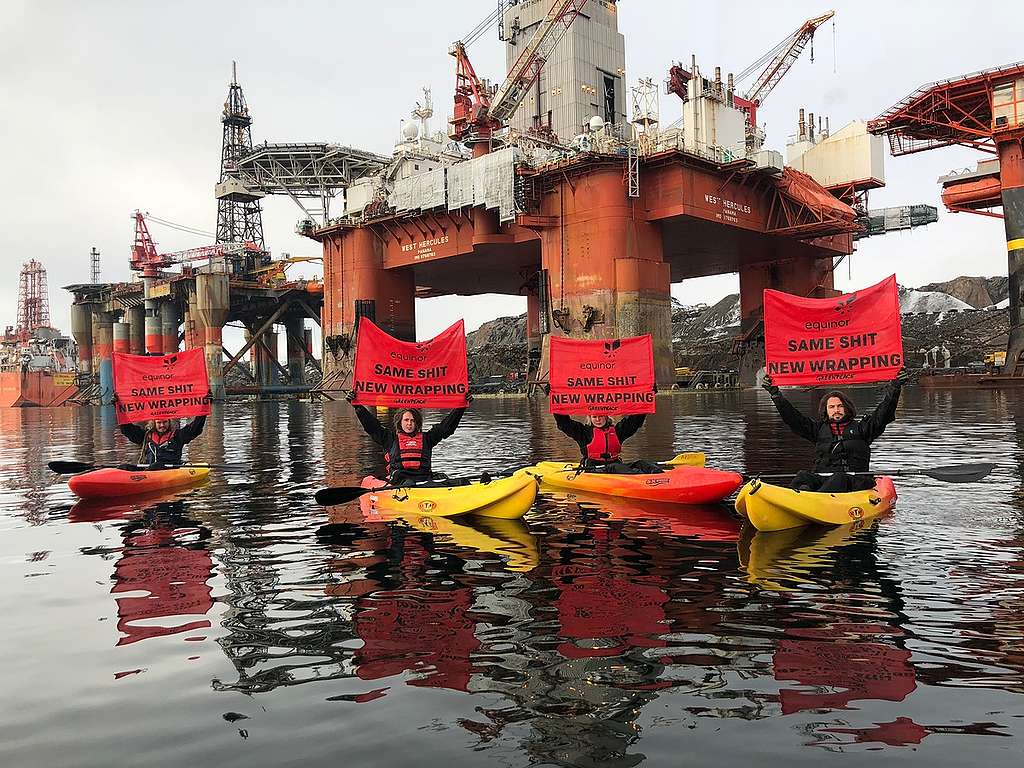 Fire kayaktivister holder opp bannere med beskjeden 'Equinor, same shit, new wrapping' I protest mot selskapets oljeboring i Arktis.© Greenpeace