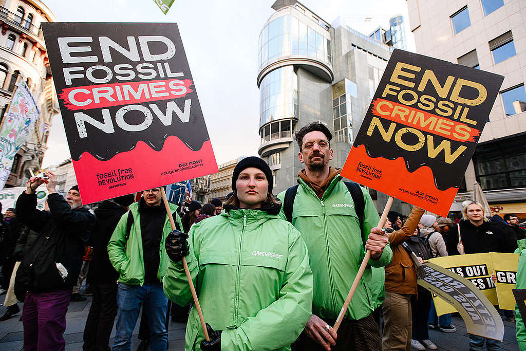 Greenpeace-aktivister holder plakater med beskjeden 'Stop Fossil Crimes Now'. © David Visnjic / Greenpeace