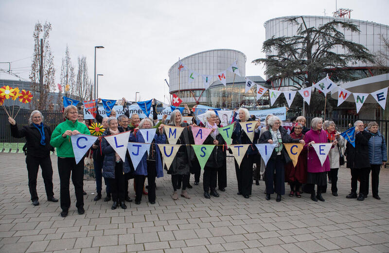 KlimaSeniorinnen samlet foran Den europeiske menneskerettighetsdomstolen i Strasbourg, Frankrike i forkant av deres storkammerhøring, med bannere som krever klimarettferdighet. 