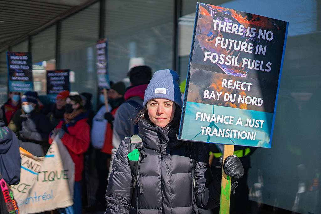 Aktivist holder et skilt med teksten 'There is no future in fossil fuels. Reject Bay Du nord. Finance a just transition'.