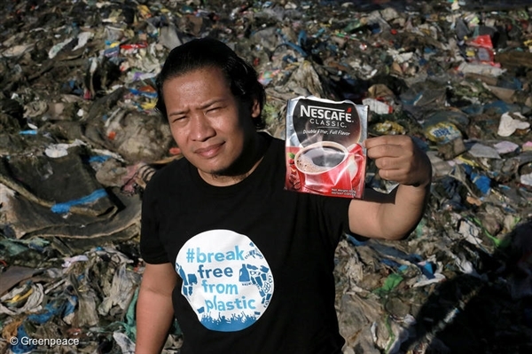 Global Anti Incineration Alliance Philippines Executive Director Froilan Grate shows a discarded pack of a Nestle product as he stands on a trash-filled shoreline along Manila Bay in Navotas City, Philippines.