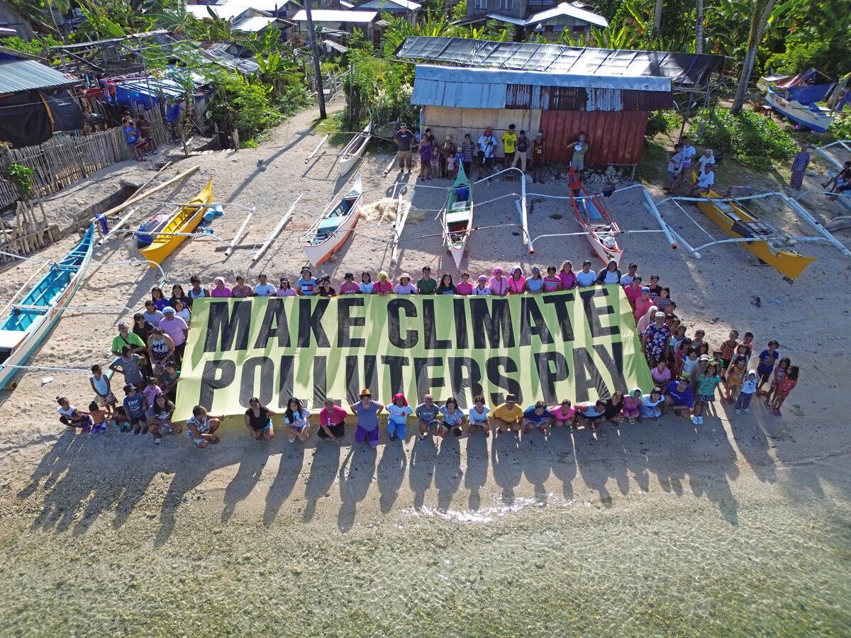 Residents of Dinagat Island in Southern Philippines hold a banner with a message: Make Climate Polluters Pay.
