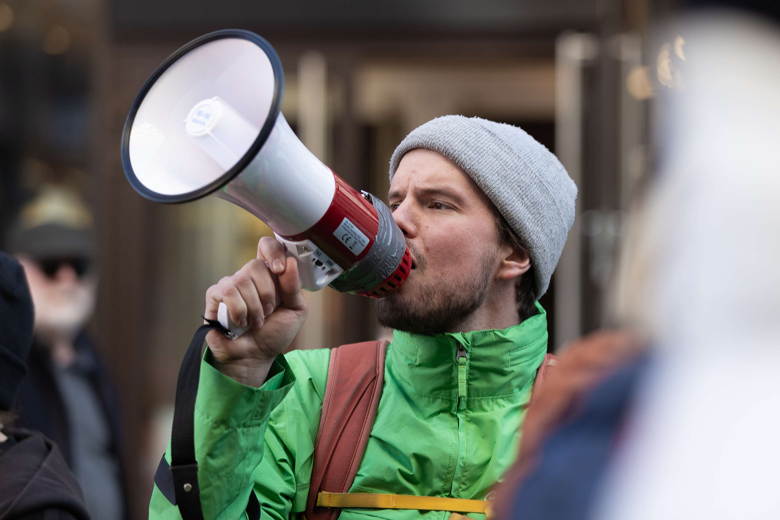 Närbild på en Greenpeace-aktivist som demonstrerar genom att prata i en megafon.