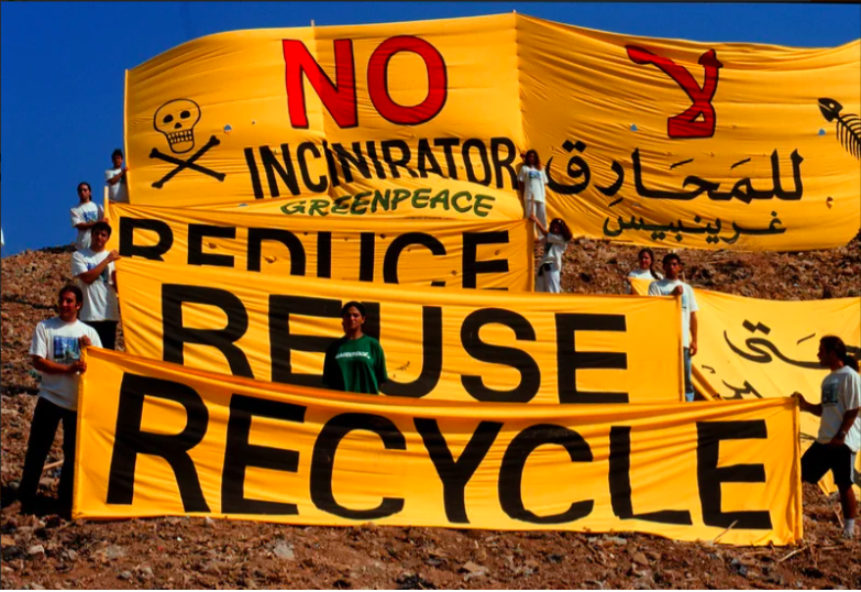 Aktivister från Greenpeace håller upp flaggor med orden: Reduce Reuse Recycle - för att protestera mot världens ohållbara överkonsumtion