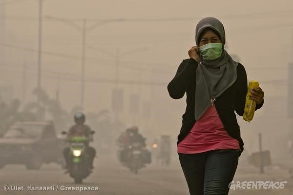 街頭的印尼女性戴著口罩躲避火燒林的霾害