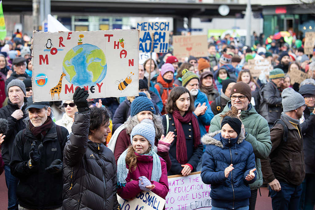 遊行倡議人士舉起標語，寫著：「More than money」，意指金錢事小，地球生態與人類安危才事關重大。
