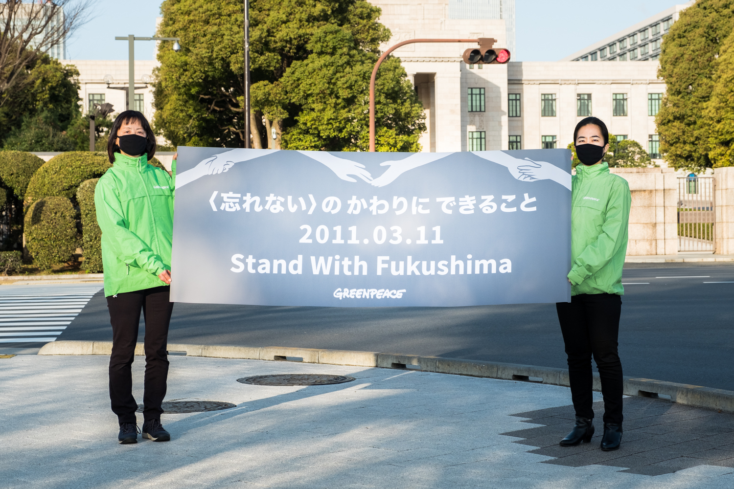 2021年3月11日，綠色和平東京辦公室在國會大廈前，手舉「與福島同行」標語，呼籲日本政府轉向再生能源的未來。