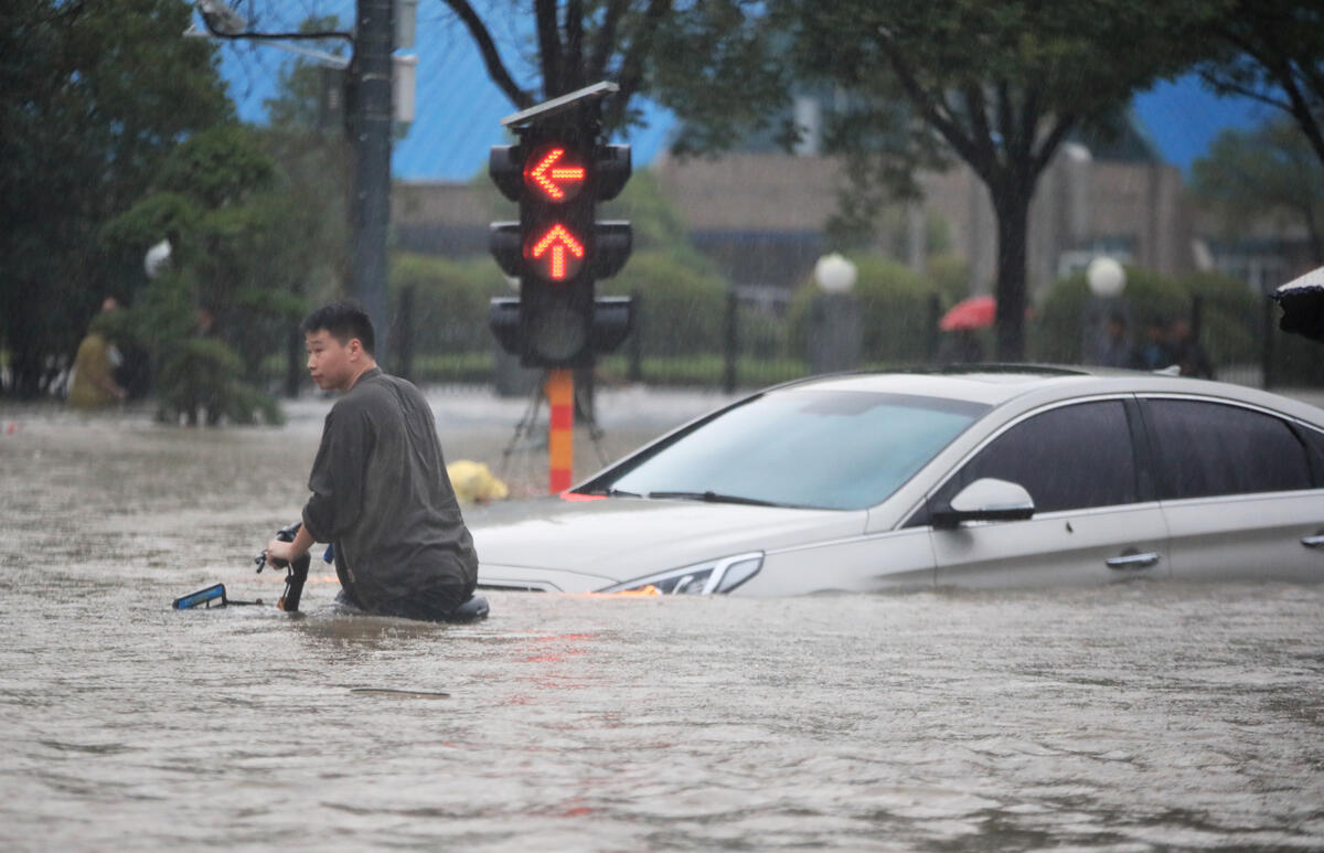 2021年7月中國鄭州遭遇暴雨，民眾在馬路上推著單車，水面高至腰間，汽車也寸步難行。© visual.people