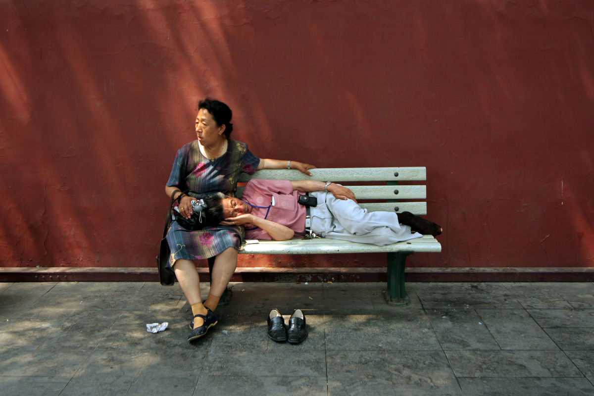 北京高溫達42度，一對老夫妻在天安門廣場附近的樹蔭下休息。