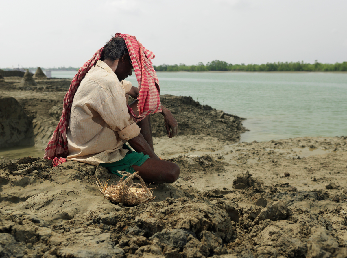 印度一位村民在攝氏40度高溫下，為了整修被洪水沖毀的河畔努力工作。圖中的他正在休息片刻。