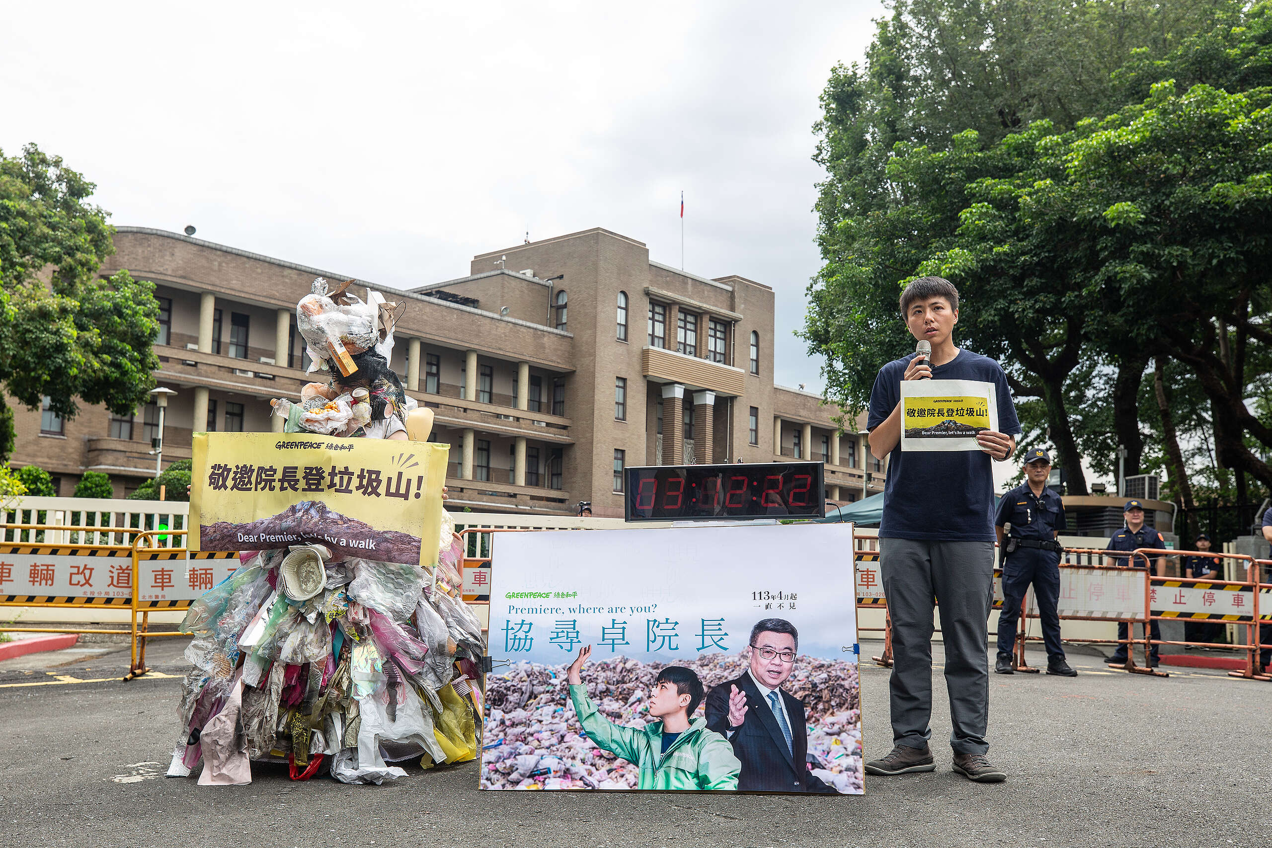 2024年8月15日，綠色和平減塑專案主任張凱婷（右）與扮成垃圾人的行動者（左）清晨 5 點駐守於行政院外，邀請卓榮泰院長親赴垃圾山。