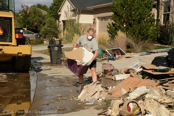 A man carries a load of ruined drywall as residents clear their houses of debris 