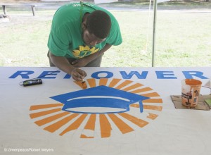 A Volunteer Paints a Banner for Repower Our Schools