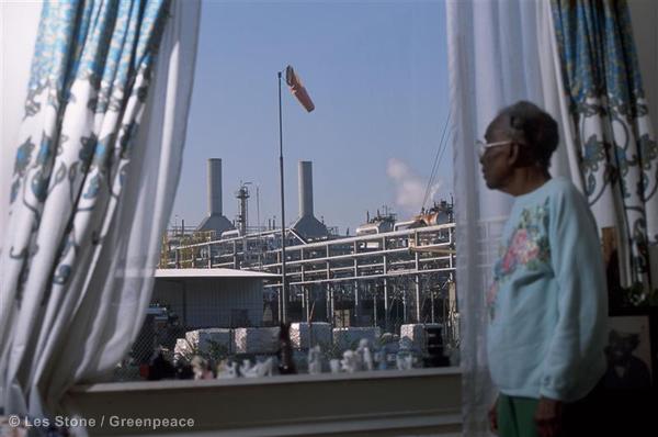 Clara Smith, 96, stands at the window of her home looking out at a Shell oil refinery just a couple of yards away.