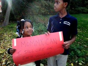 Kids hold a sign that reads "Mommy, can I still live on Earth when I grow up?"