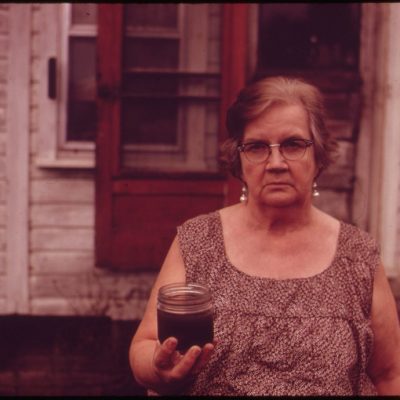 Mary Workman Holds A Jar of Undrinkable Water That Comes from Her Well