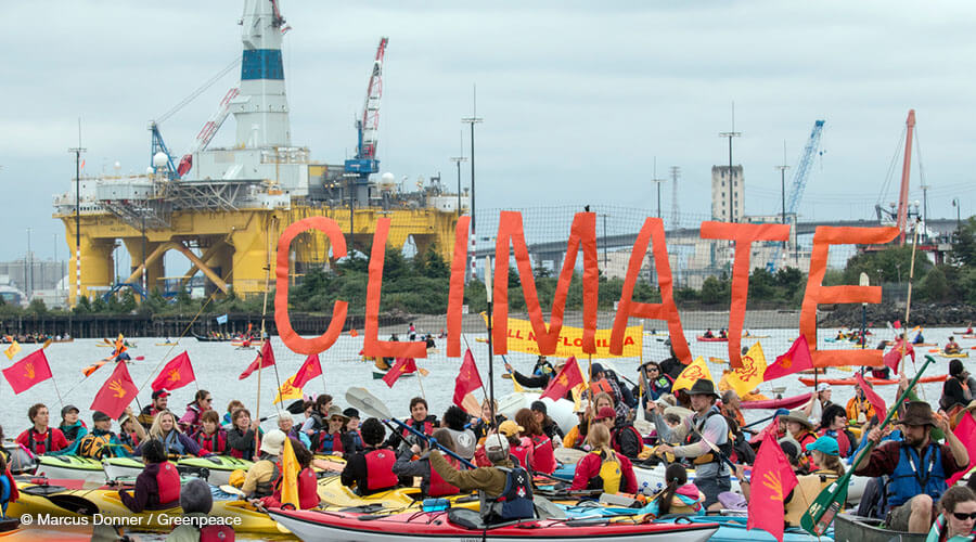Activists raise a "Climate" banner in the sHell No Flotilla in the 'Paddle in Seattle' protest