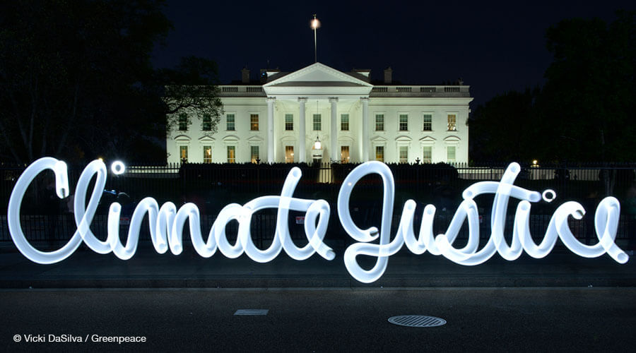 Light graffiti reading "Climate Justice" in front of the White House