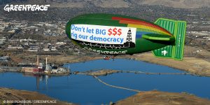 The Greenpeace Thermal Airship flies a banner that reads “Don't Let Big $$$ Rig our Democracy.”