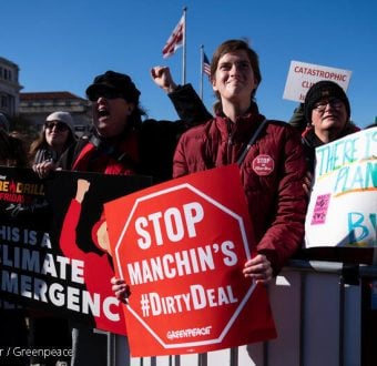 Climate activist holds sign reading Stop Manchin's #DirtyDeal